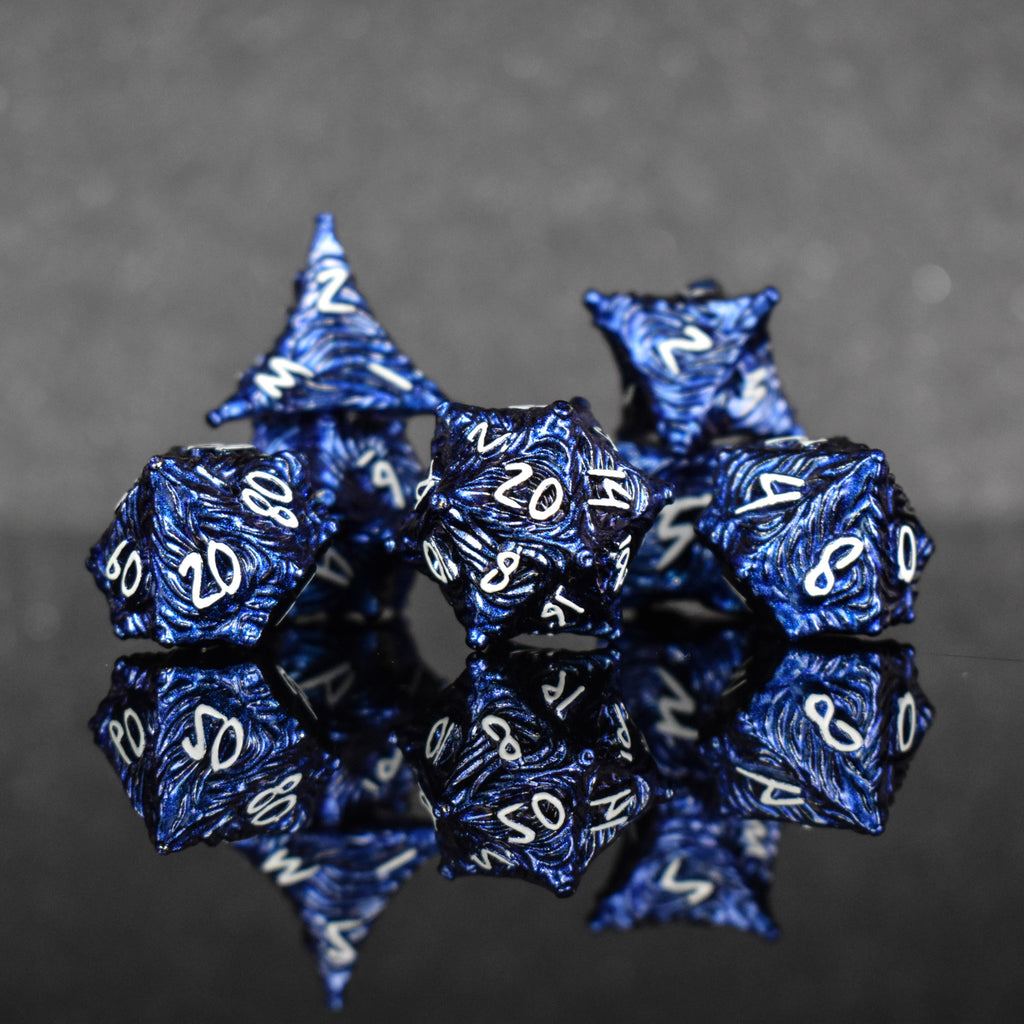 a set of dark blue metal dice with vortex swirls and a white font