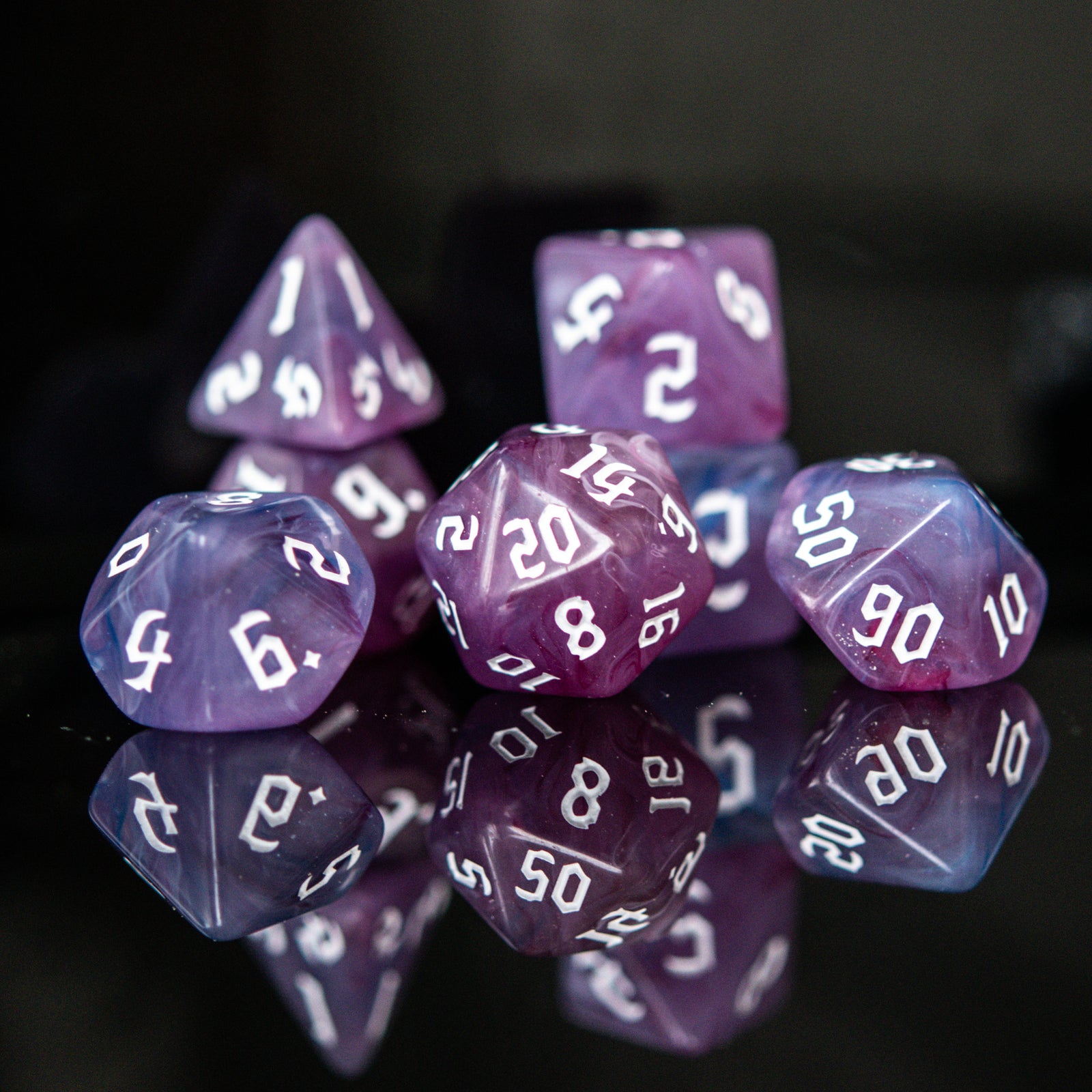 A set of purple shades of acrylic dice with engraved white numbers 