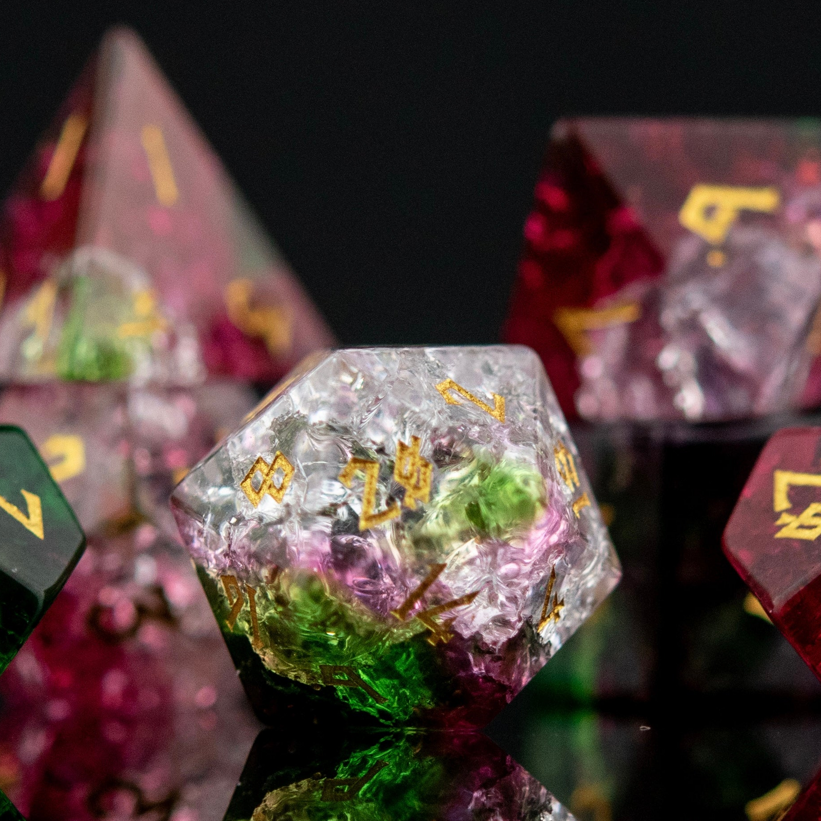 A set of hand-carved, multicolored glass dice with shattered glass effect and engraved numbers, displayed on a reflective surface.