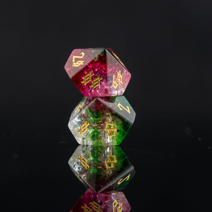 A set of hand-carved, multicolored glass dice with shattered glass effect and engraved numbers, displayed on a reflective surface.
