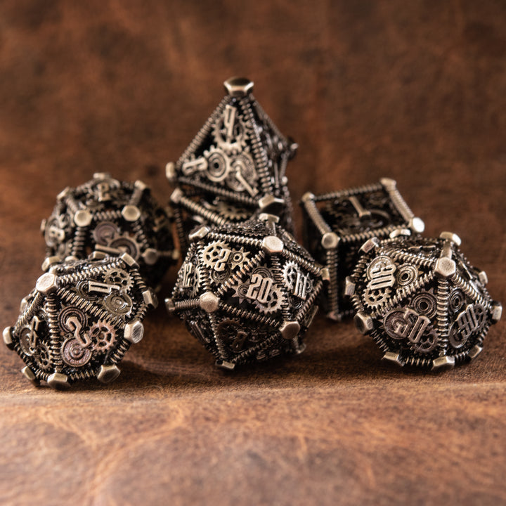 A set of silver metal hollow dice with embossed numbers, including various shapes typical for role-playing games, displayed on a textured background.