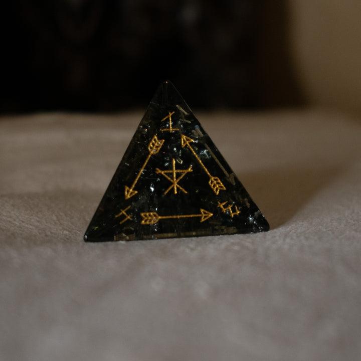 hand-carved, smoky-gray glass dice with gold engraved numbers and wendigo inspired details, displayed against a black background.