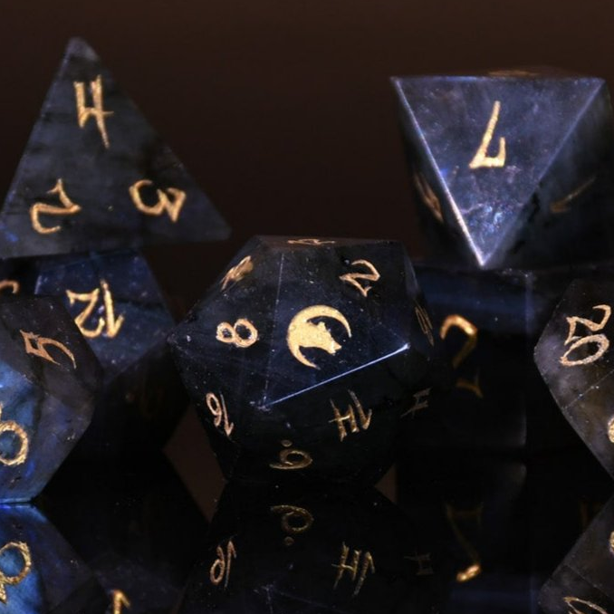 A collection of black dice with engraved numbers, displayed against a dark background.