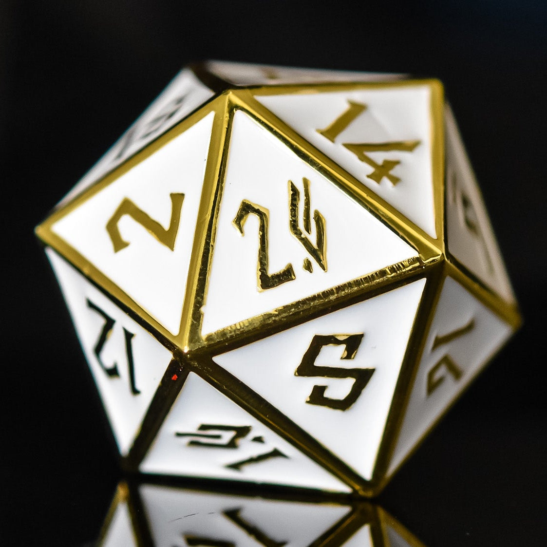 A single 35mm white and gold metal D20 dice with embossed numbers placed on a reflective surface.