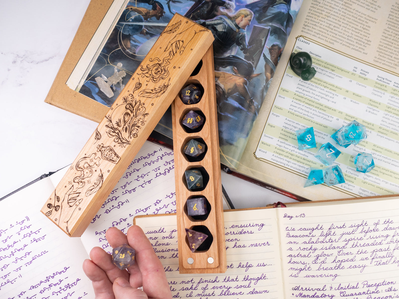Wooden dice holder with engraved designs on a table with books and papers.