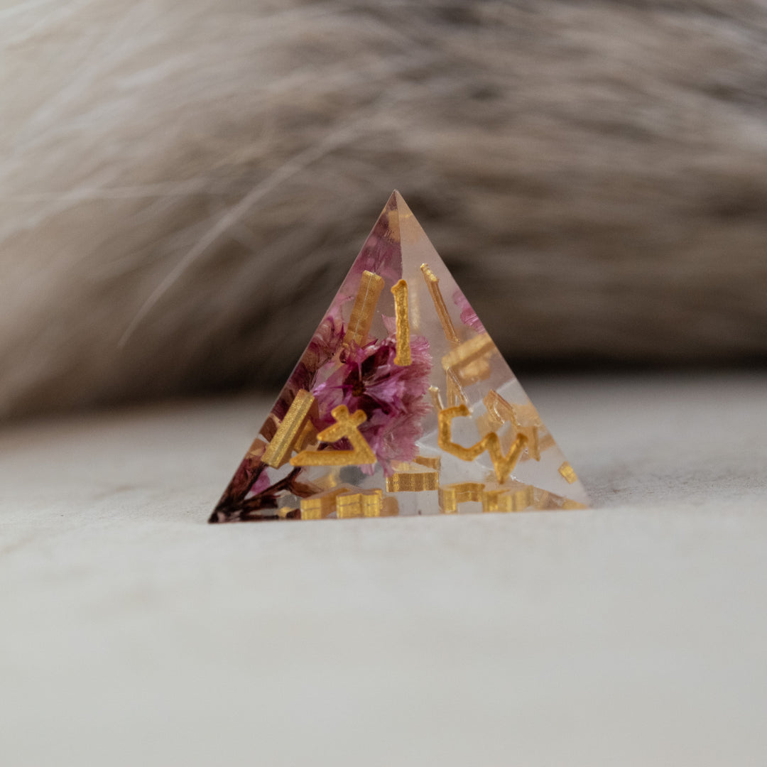 A set of clear sharp-edged resin dice with hand-painted gold numbers, featuring pink florals inside for dungeons and dragons and tabletop gaming