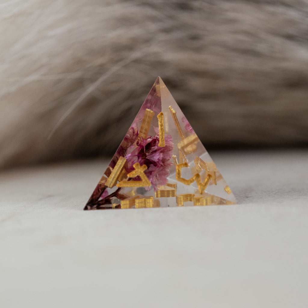 A set of clear sharp-edged resin dice with hand-painted gold numbers, featuring pink florals inside for dungeons and dragons and tabletop gaming