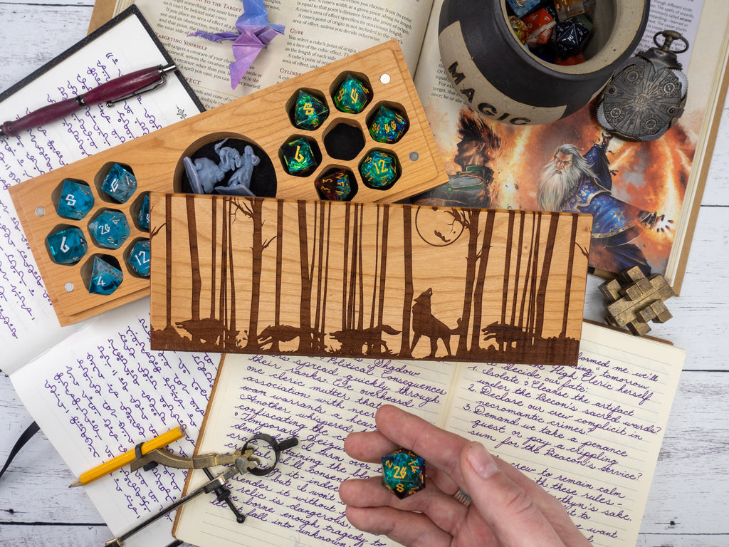 Wooden dice tray with engraved design, surrounded by fantasy-themed items on a wooden surface.