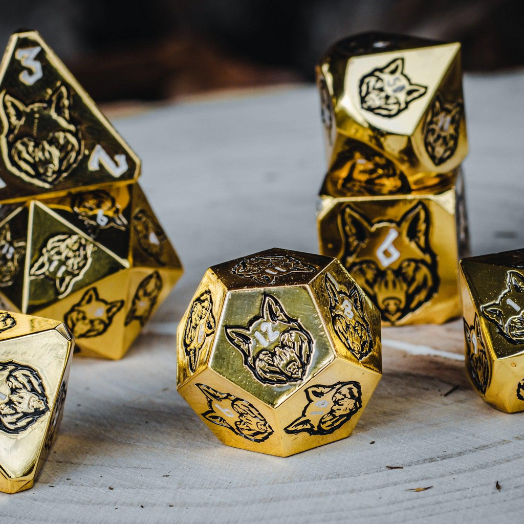 A set of gold metal dnd dice with black wolf designs and white numbers