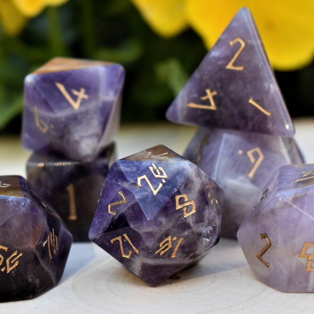 An amethyst stone dice set featuring gold numbers in a Nordic font