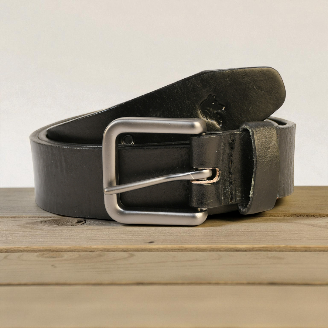 Black leather belt with a silver buckle on a wooden surface