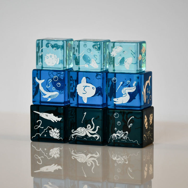 Stack of blue and black cubes with underwater-themed illustrations on a reflective surface.