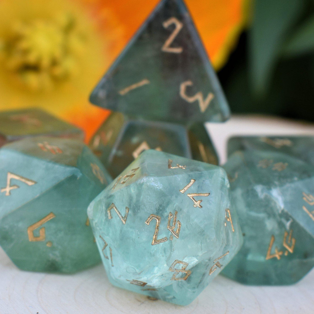 Set of green polyhedral dice with gold numbers on a blurred background