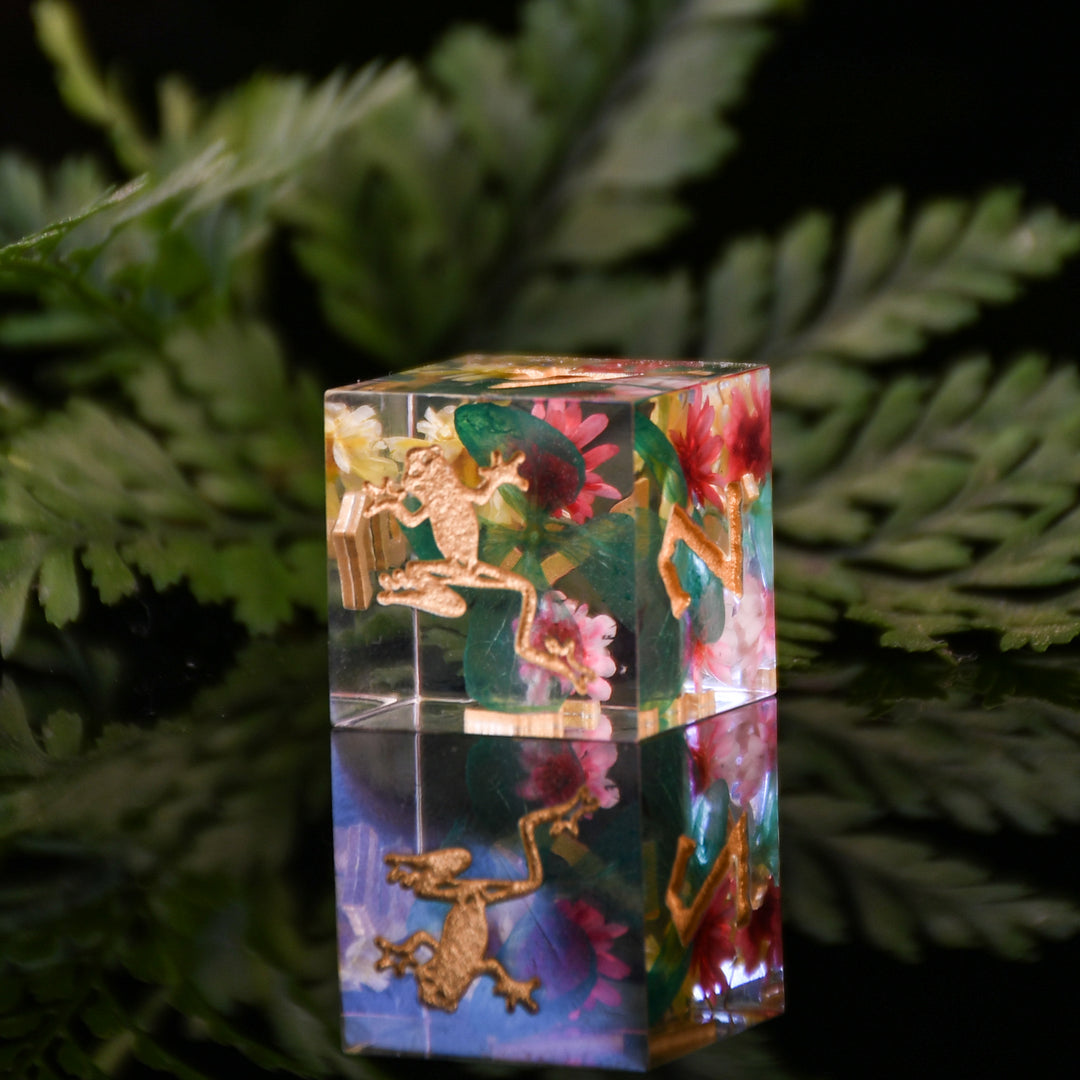 Crystal block with engraved design of a frog and flowers on a dark background
