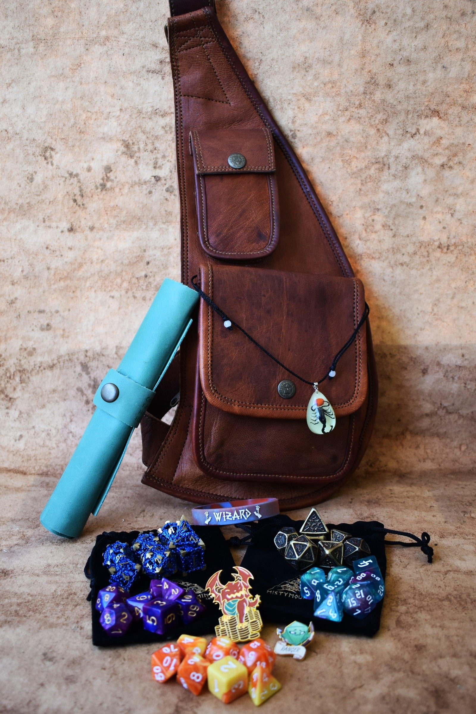A brown leather sling mystery dice bag with examples of the items within