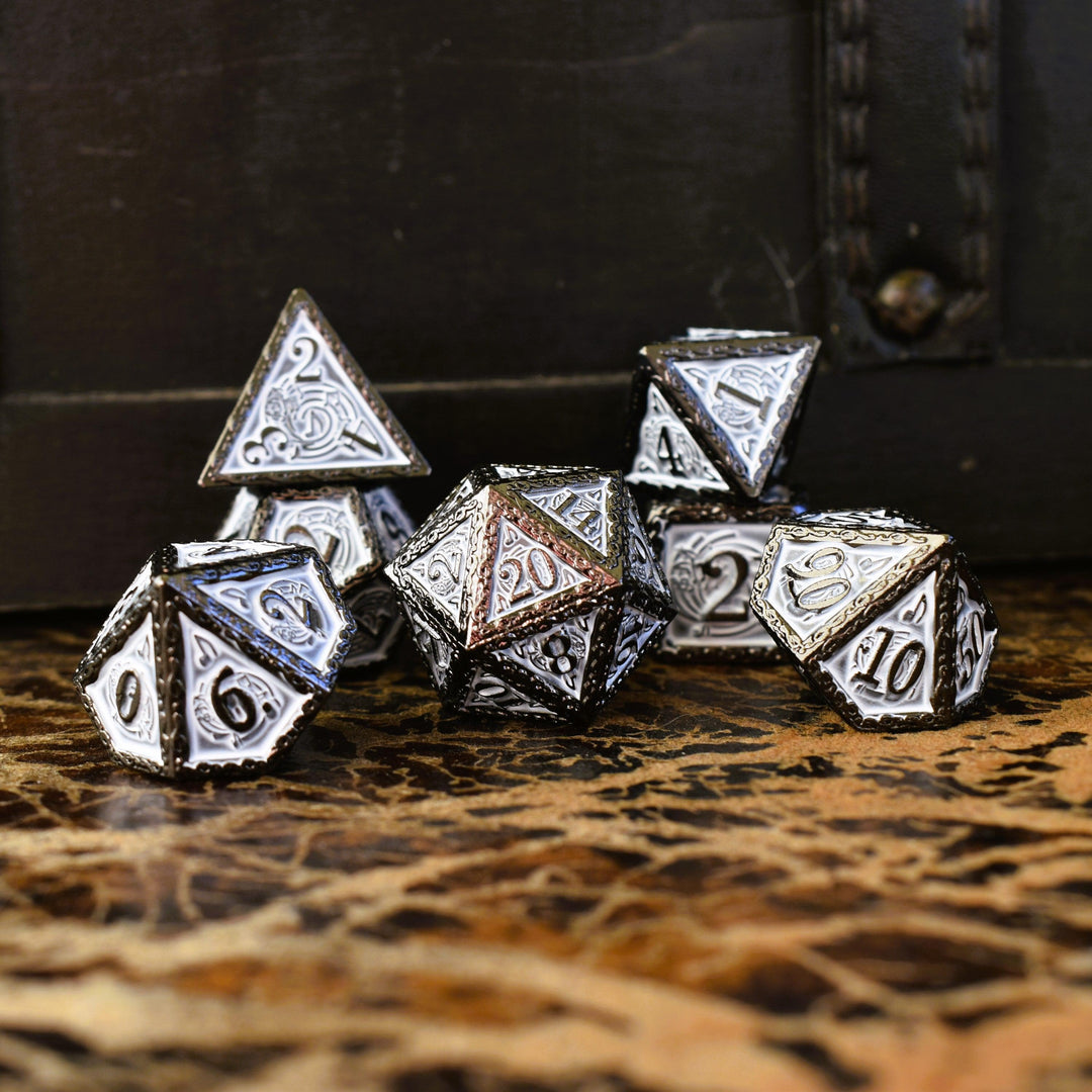 A set of white and gunmetal gray metal dice with musical note details around the gunmetal grey numbers on a wooden surface, including various shapes such as a d4, d6, d8, d10, d12, and d20.