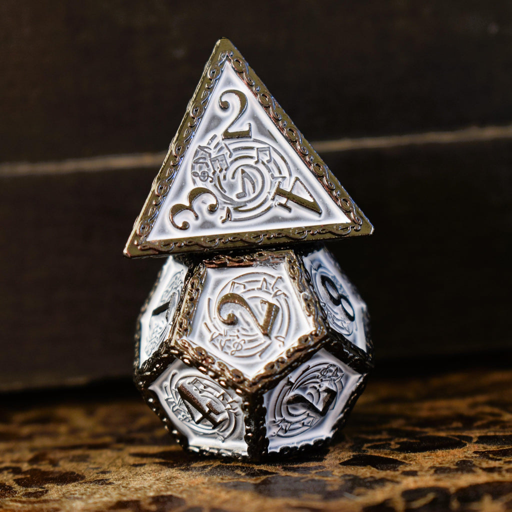 A set of white and gunmetal gray metal dice with musical note details around the gunmetal grey numbers on a wooden surface, including various shapes such as a d4, d6, d8, d10, d12, and d20.