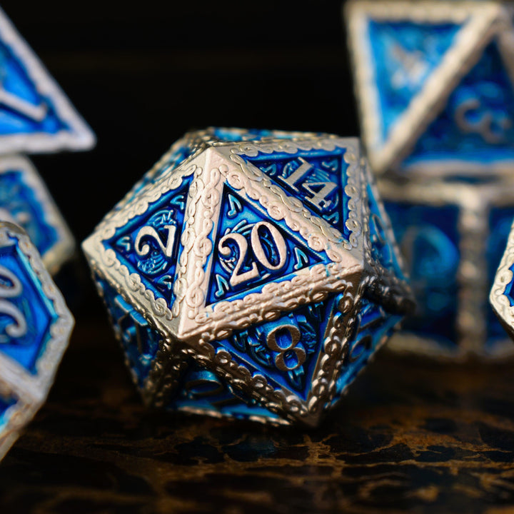 A set of blue and silver metal dice with musical note details around the silver numbers on a wooden surface, including various shapes such as a d4, d6, d8, d10, d12, and d20.