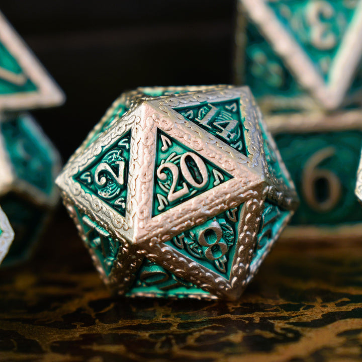 A set of green and silver metal dice with musical note details around the silver numbers on a wooden surface, including various shapes such as a d4, d6, d8, d10, d12, and d20.