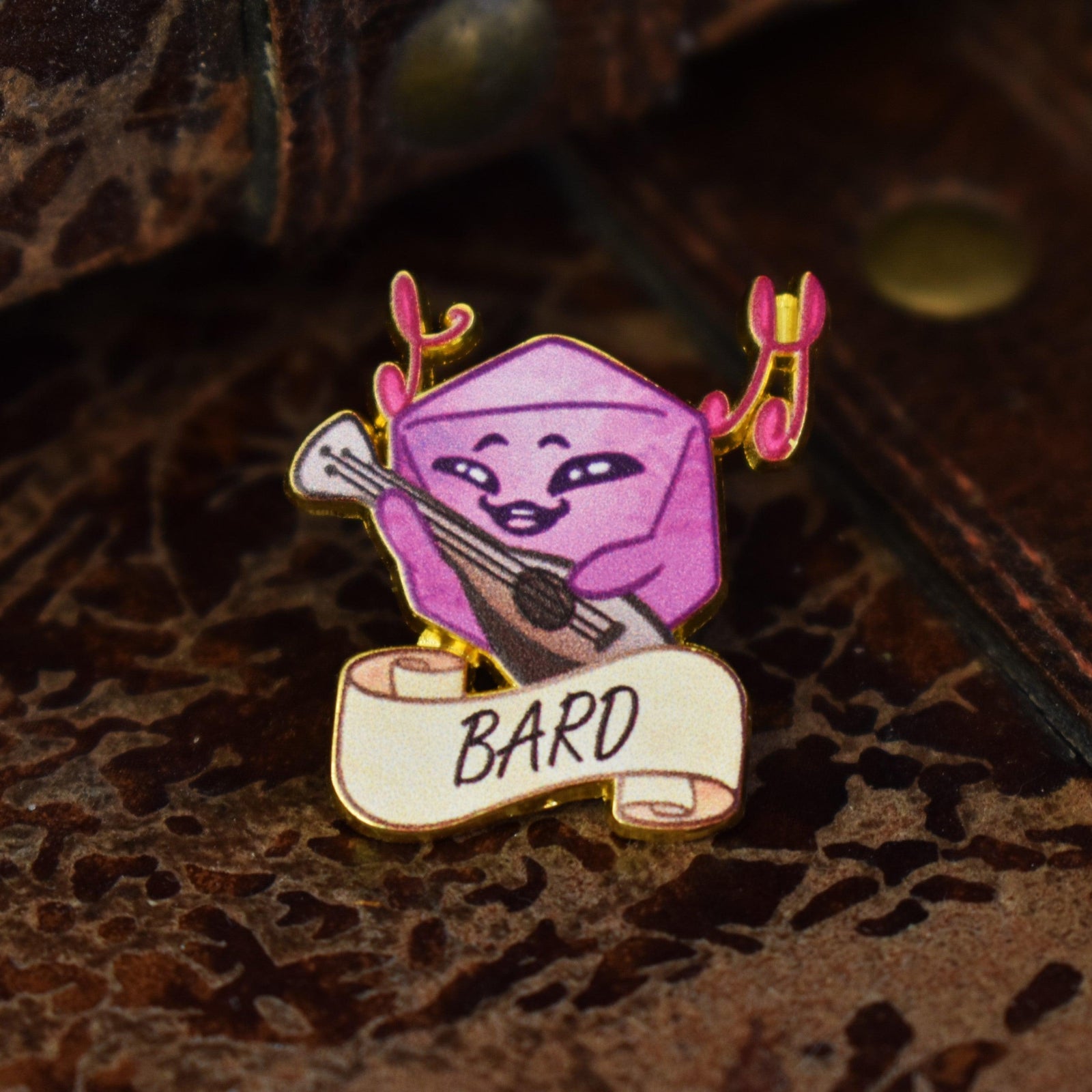 A colorful enamel pin depicting a character with a guitar and a scroll labeled 'BARD'.