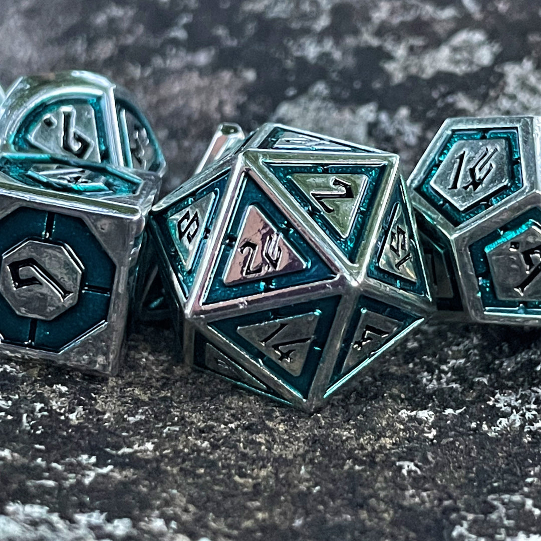 A set of metal dice with aqua and silver colors, including specific numbers for dungeons and dragons tabletop gaming