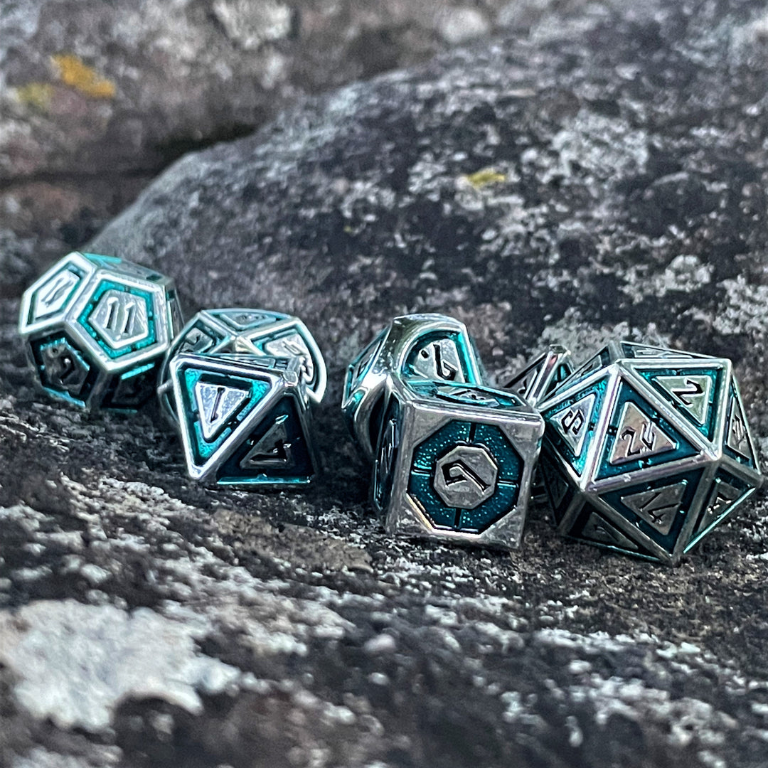 A set of metal dice with aqua and silver colors, including specific numbers for dungeons and dragons tabletop gaming