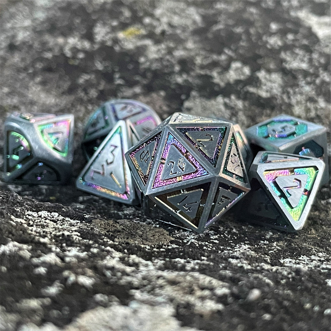A set of silver metal dnd dice with iridescent properties, including engraved numbers, displayed on a rocky surface.