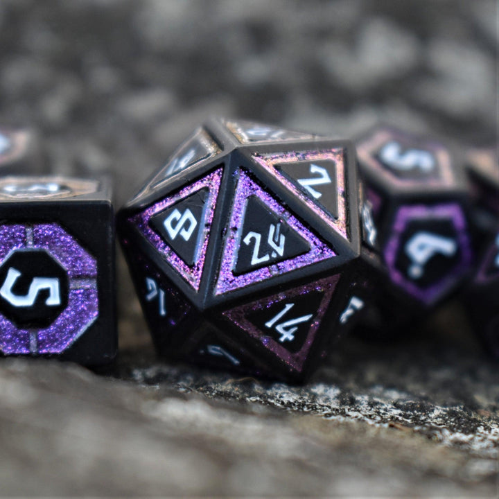 A set of black metal dice with purple glitter borders on each face and white numbering for wargaming tabletop gaming and board games
