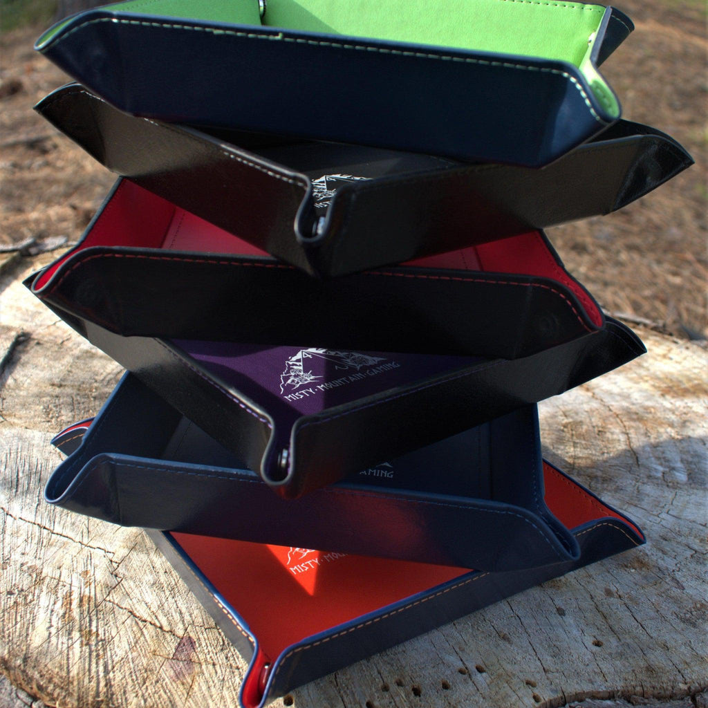 A collapsible dice tray made of poly-leather, featuring the Misty Mountain Gaming logo, placed on a wooden surface.
