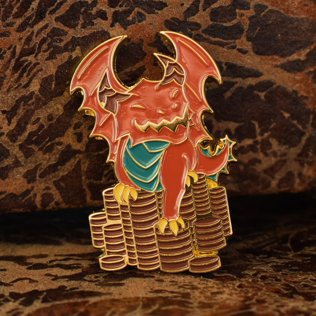 A metal enamel pin shaped like a red dnd dragon sitting on top of a stack of gold coins.