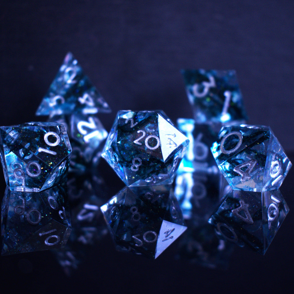 A set of sharp-edged resin dnd dice in blue with silver numbers and black and glitter details inside for ttrpg and board games