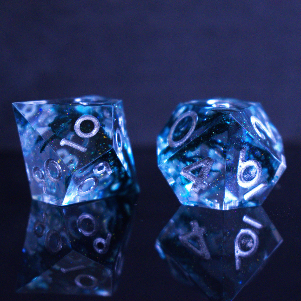 A set of sharp-edged resin dnd dice in blue with silver numbers and black and glitter details inside for ttrpg and board games