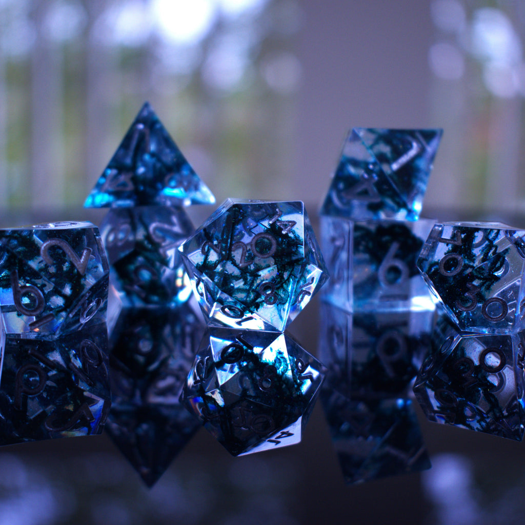 A set of sharp-edged resin dnd dice in blue with silver numbers and black and glitter details inside for ttrpg and board games