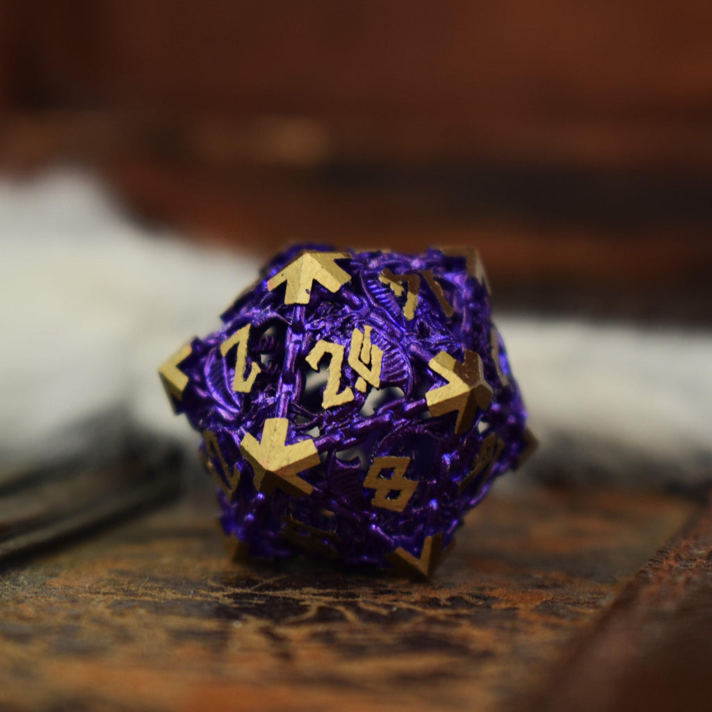 A set of purple hollow metal dice with gold embossed numbers, including various shapes such as a D4, D6, D8, D10, D12, and D20, displayed on a wooden surface.