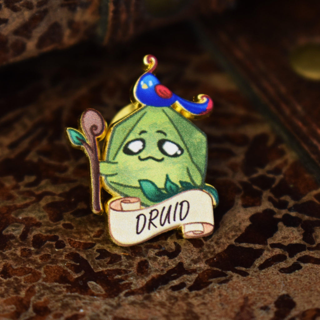 A colorful enamel pin depicting a cartoon-style druid character with a staff and a scroll that reads 'DRUID'.