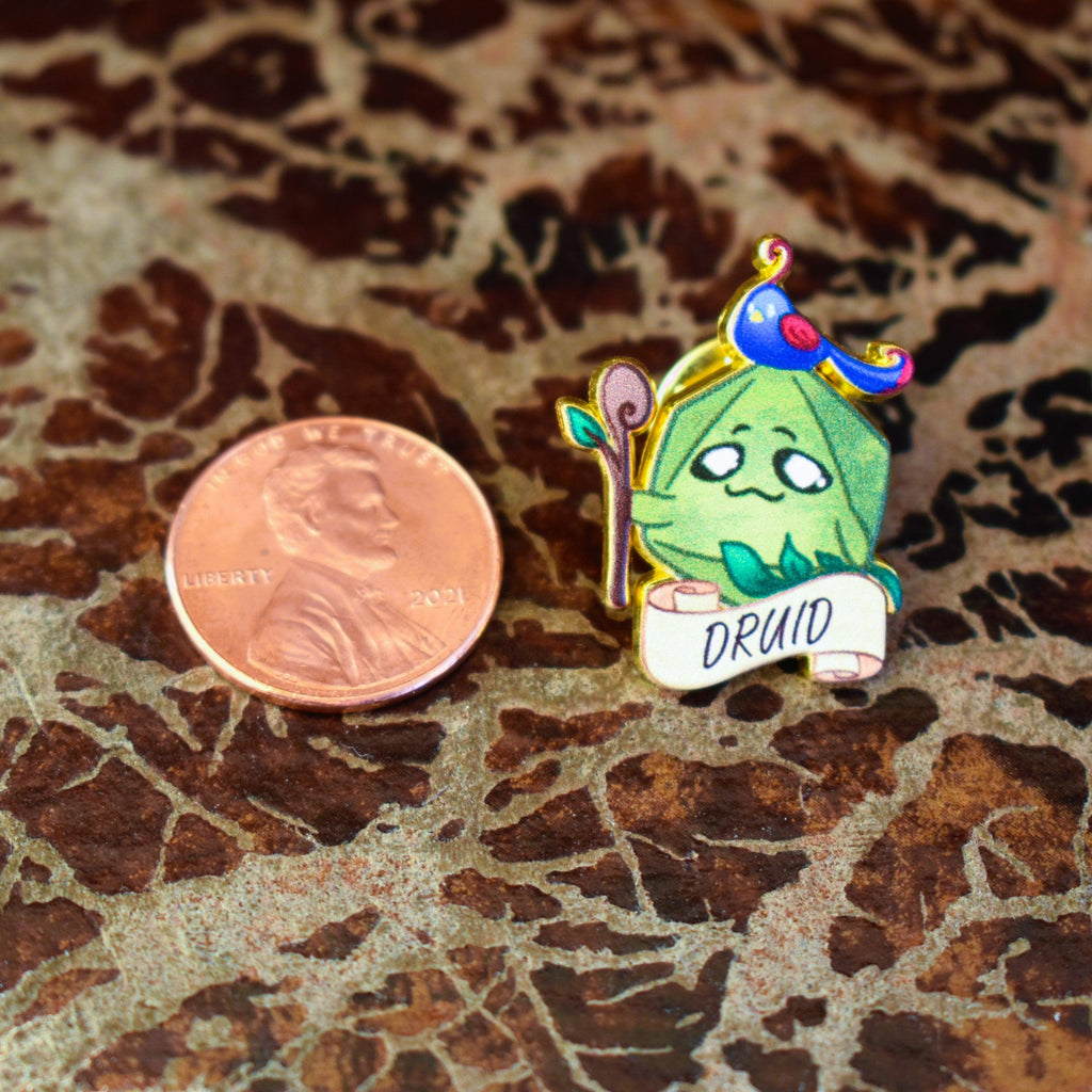 A colorful enamel pin depicting a cartoon-style druid character with a staff and a scroll that reads 'DRUID'.