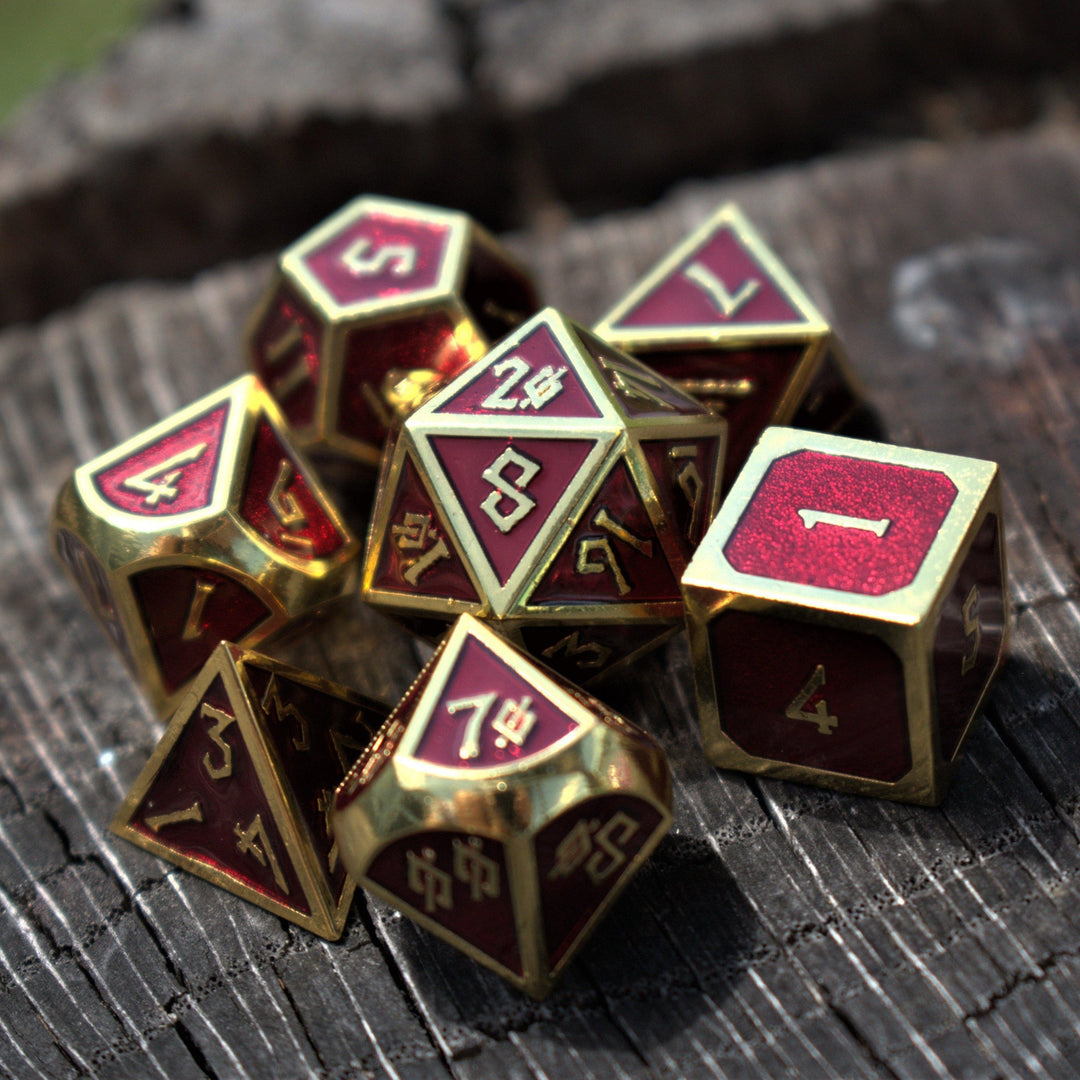 A set of deep royal red metal dnd dice with gold edges and borders, and gold numbering in a nordic font for wargaming tabletop gaming and board games