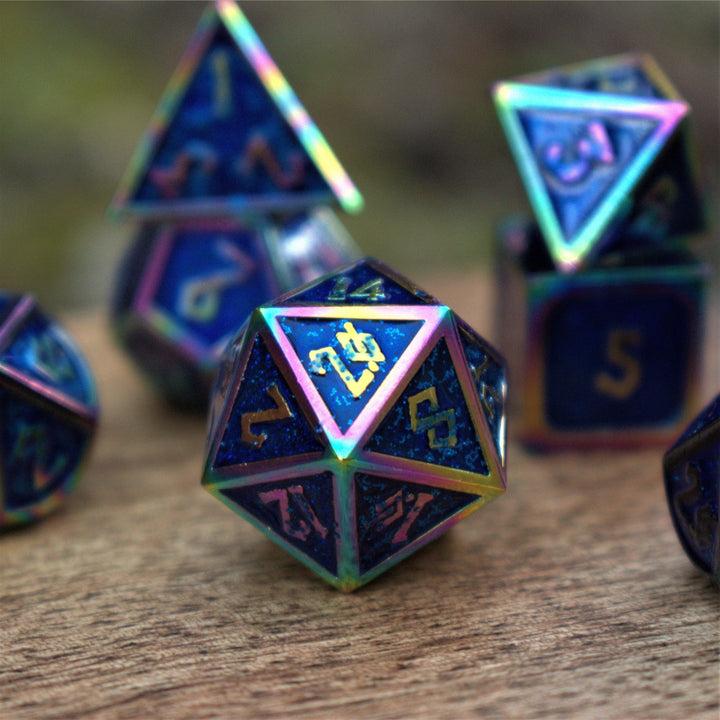 A set of metal dice with blue iridescent glitter coating and embossed golden numbers, displayed on a wooden surface.