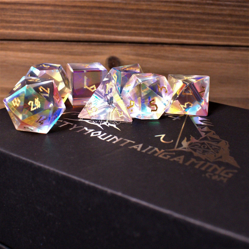 A set of iridescent glass dice with engraved numbers, including various shapes such as a four-sided die (D4), six-sided die (D6), eight-sided die (D8), ten-sided dice (D10), twelve-sided die (D12), and twenty-sided die (D20).
