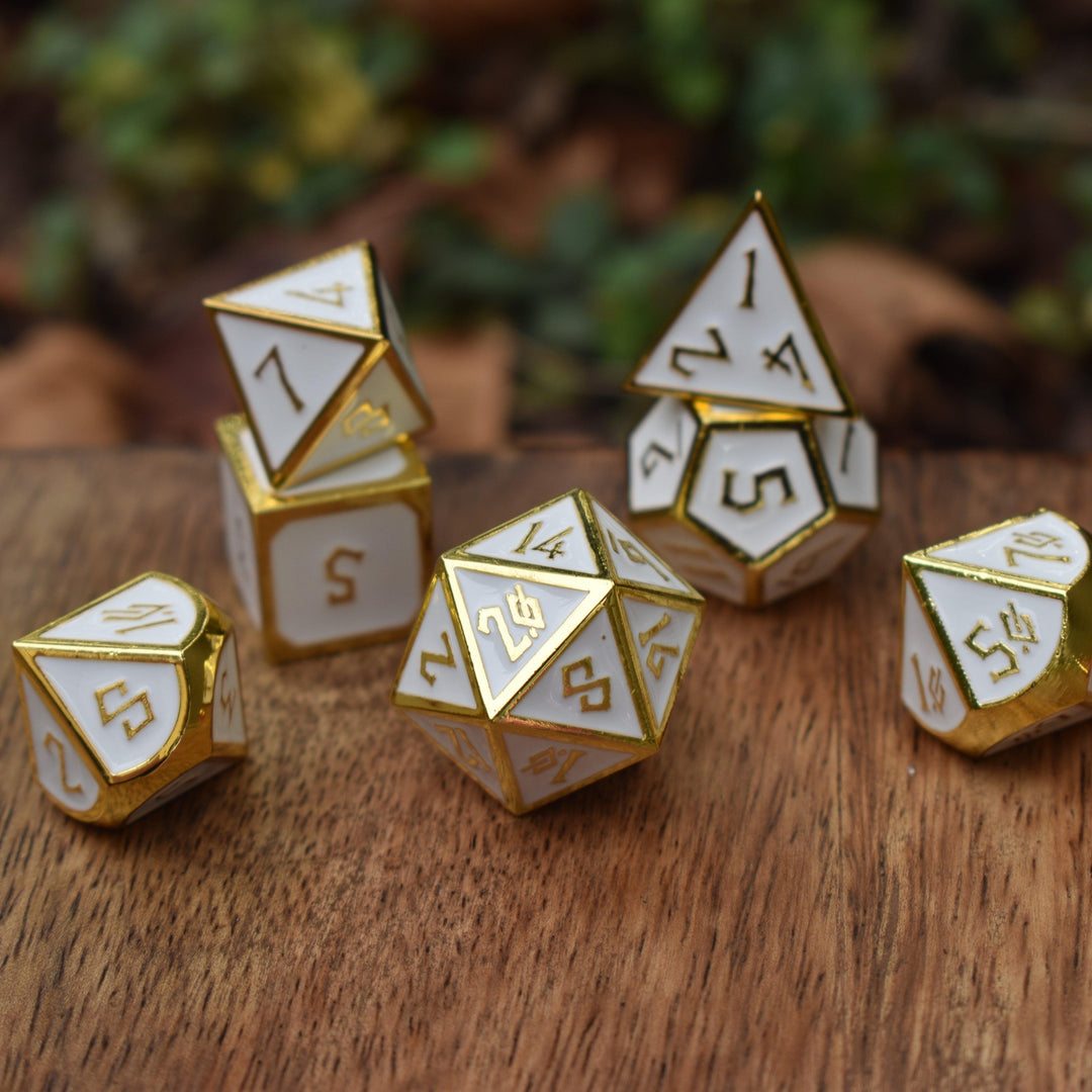 A set of white metal dnd dice with gold borders and numbers for tabletop gaming wargaming and board games
