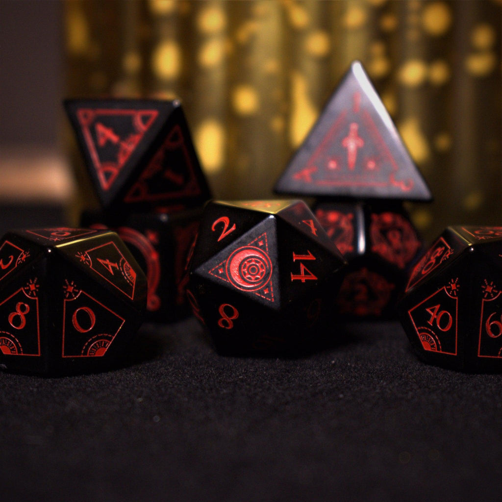 A set of black Obsidian gemstone dice with red engraved numbers and symbols, including a D4, D6, D8, two D10s, D12, and D20, displayed on a dark surface with a blurred light background.