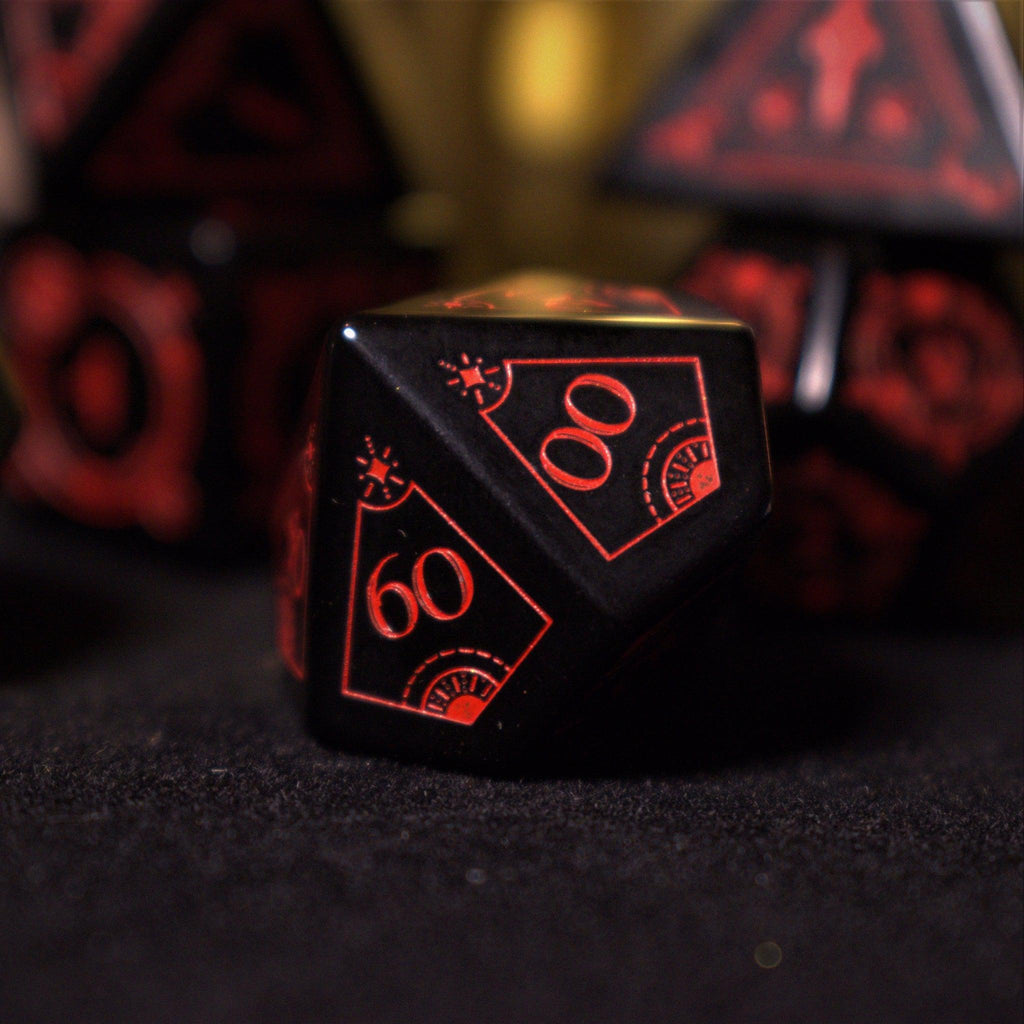 A set of black Obsidian gemstone dice with red engraved numbers and symbols, including a D4, D6, D8, two D10s, D12, and D20, displayed on a dark surface with a blurred light background.