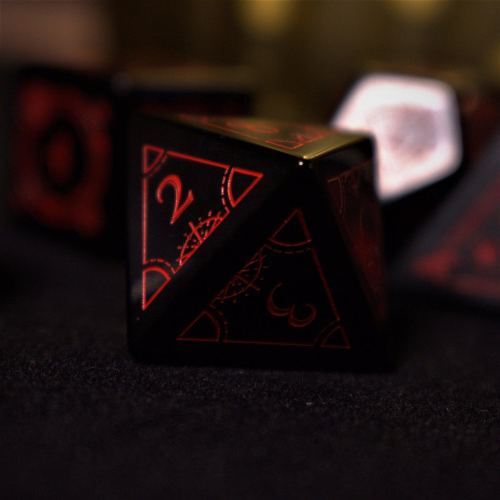 A set of black Obsidian gemstone dice with red engraved numbers and symbols, including a D4, D6, D8, two D10s, D12, and D20, displayed on a dark surface with a blurred light background.