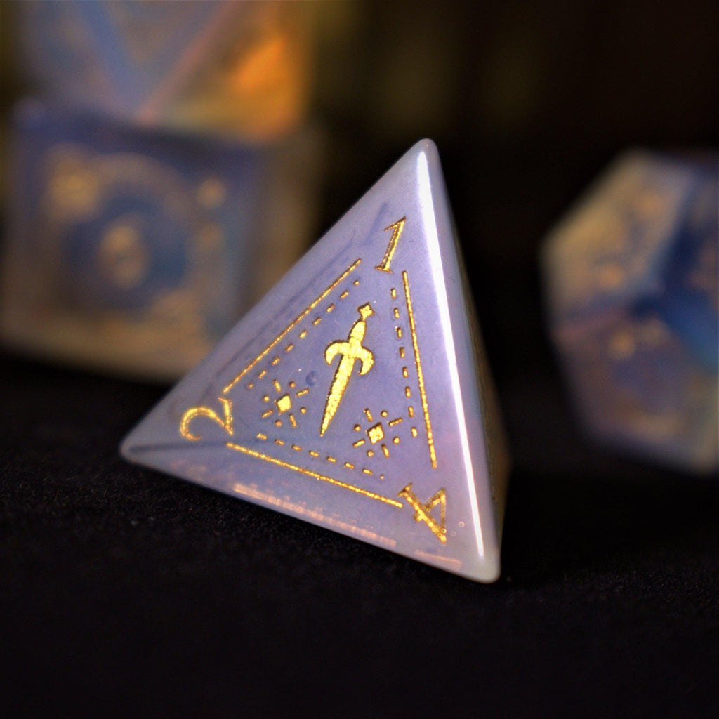 A collection of hand-carved, opalescent white gemstone dnd dice with engraved numbers, displayed on a dark surface.