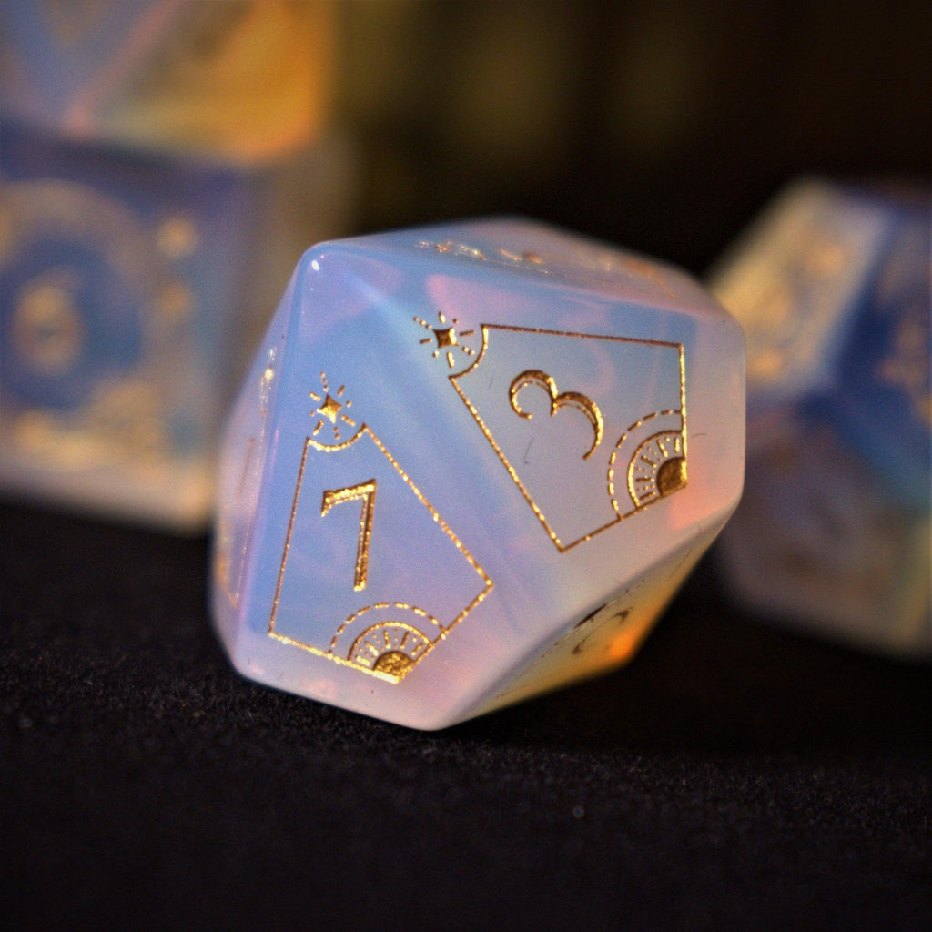 A collection of hand-carved, opalescent white gemstone dnd dice with engraved numbers, displayed on a dark surface.