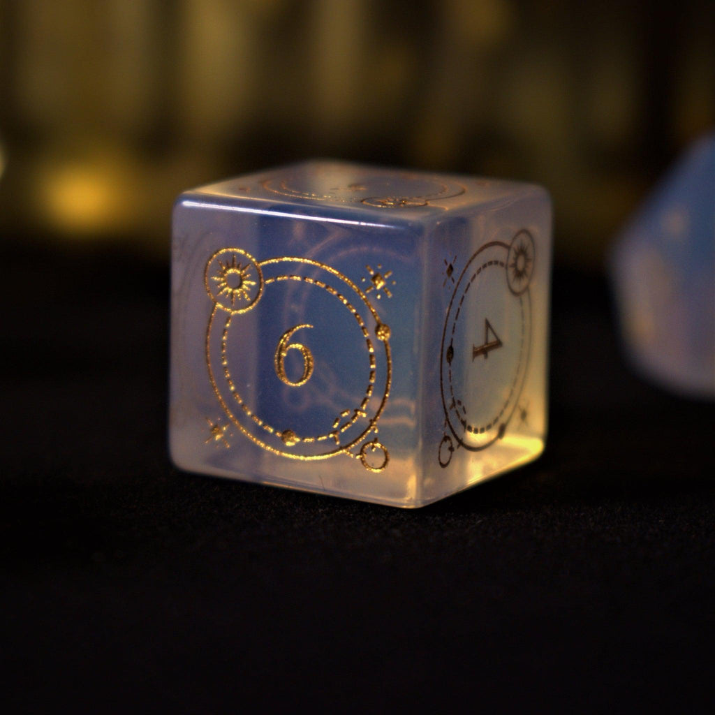 A collection of hand-carved, opalescent white gemstone dnd dice with engraved numbers, displayed on a dark surface.