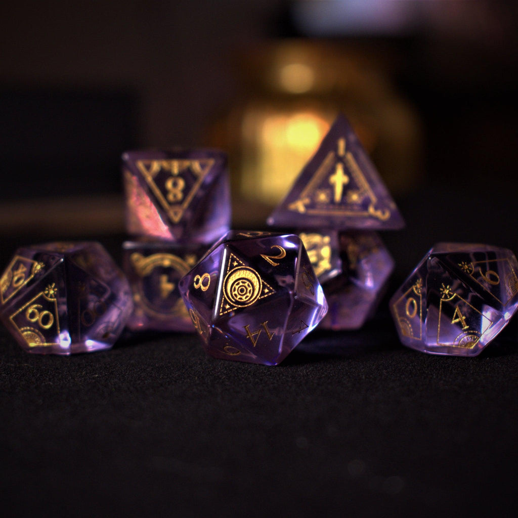 A set of purple glass dice with engraved golden numbers and detail, displayed on a dark surface with a light source in the background creating a reflective sheen on the dice.