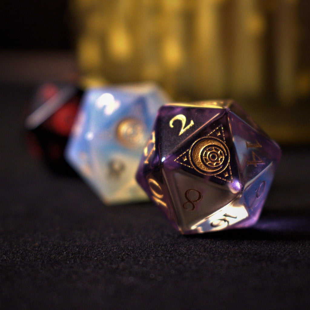 A set of purple glass dice with engraved golden numbers and detail, displayed on a dark surface with a light source in the background creating a reflective sheen on the dice.