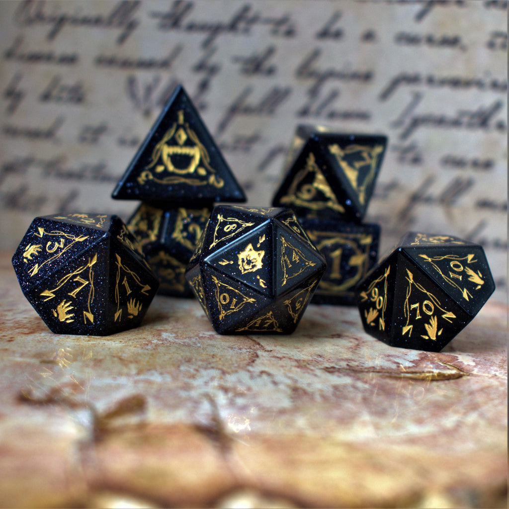 A set of Fangs of Winter Blue Sandstone Stone Dice with gold engravings on a textured background.