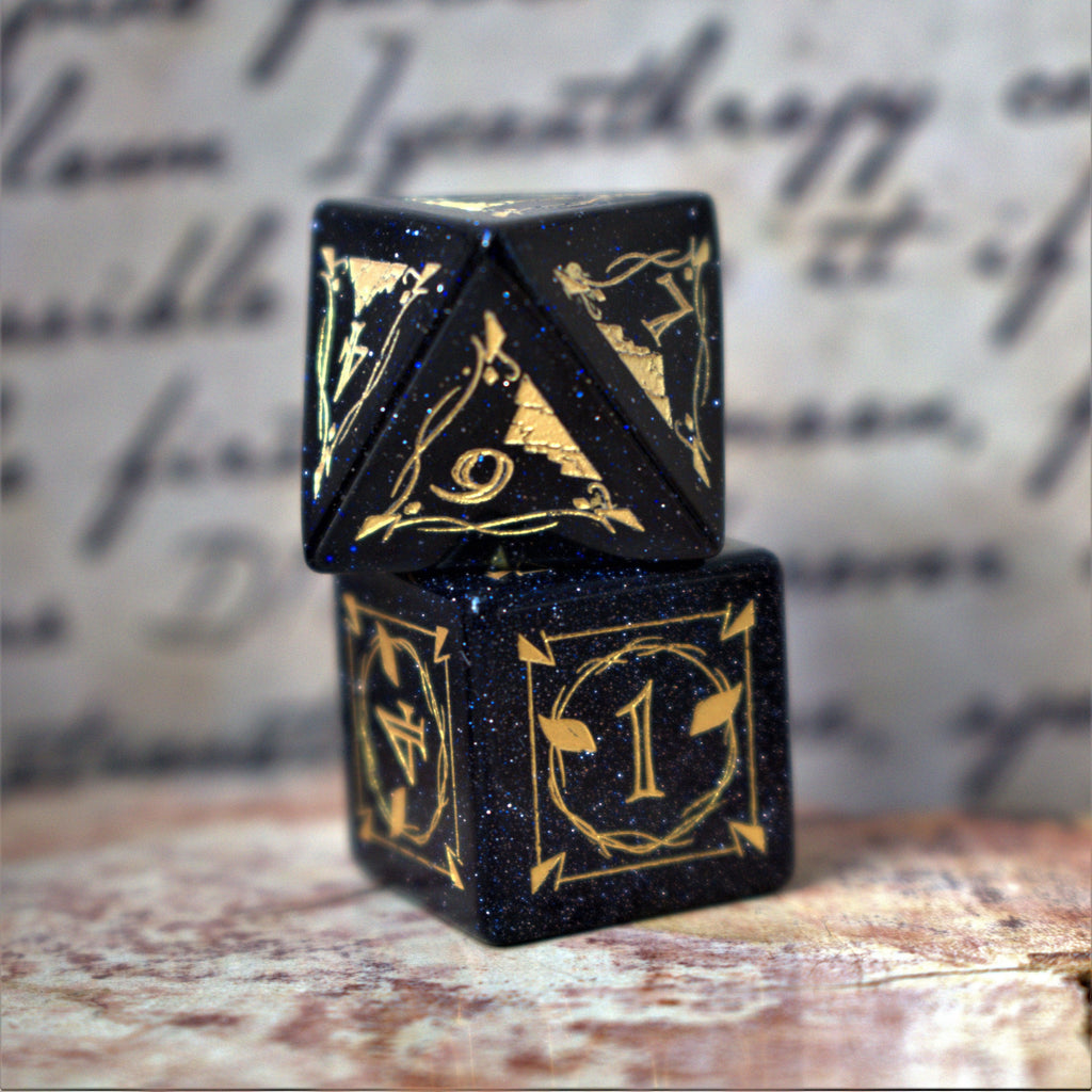 A set of Fangs of Winter Blue Sandstone Stone Dice with gold engravings on a textured background.